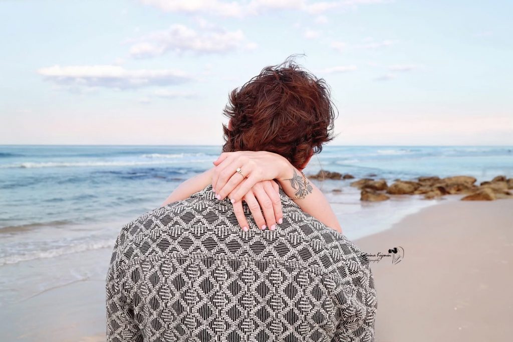 Romantic engagement photography session in Palm Coast, Florida, featuring a couple embracing outdoors in natural light.