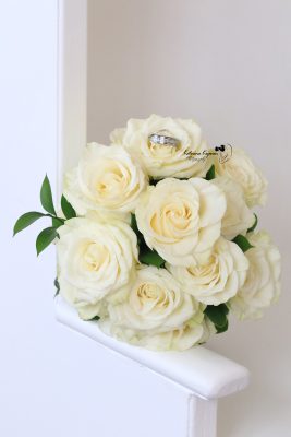 Close-up wedding photography of a bridal bouquet and wedding rings, capturing the elegant details of the wedding day.