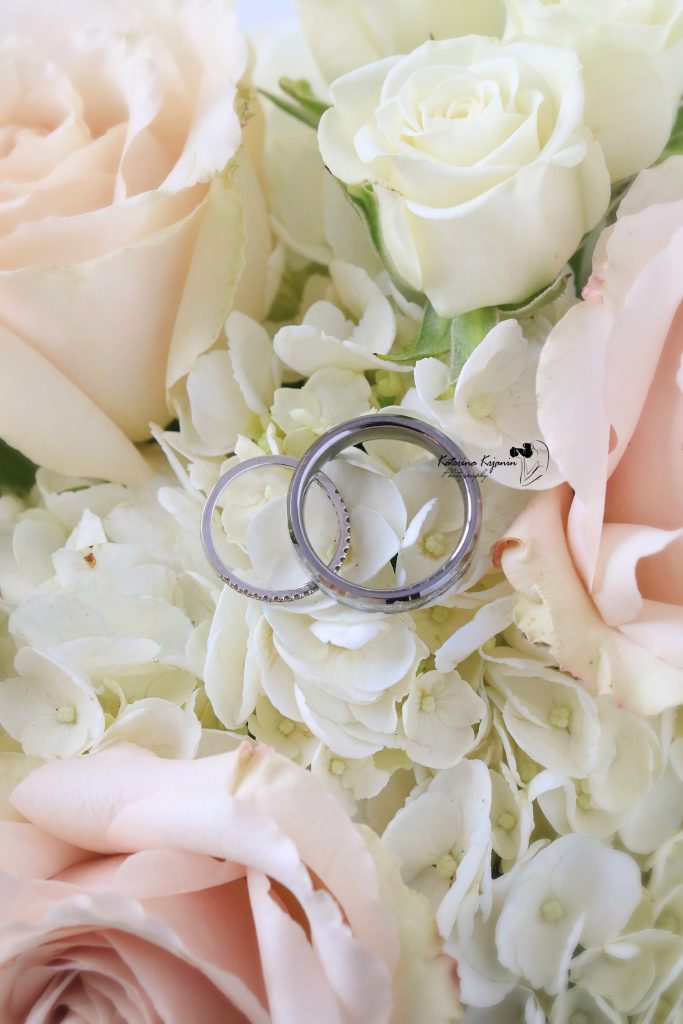 Close-up wedding photography of a bridal bouquet and wedding rings, capturing the elegant details of the wedding day.