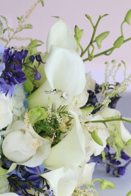 Close-up wedding photography of a bridal bouquet and wedding rings, capturing the elegant details of the wedding day.