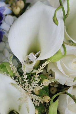 Close-up wedding photography of a bridal bouquet and wedding rings, capturing the elegant details of the wedding day.